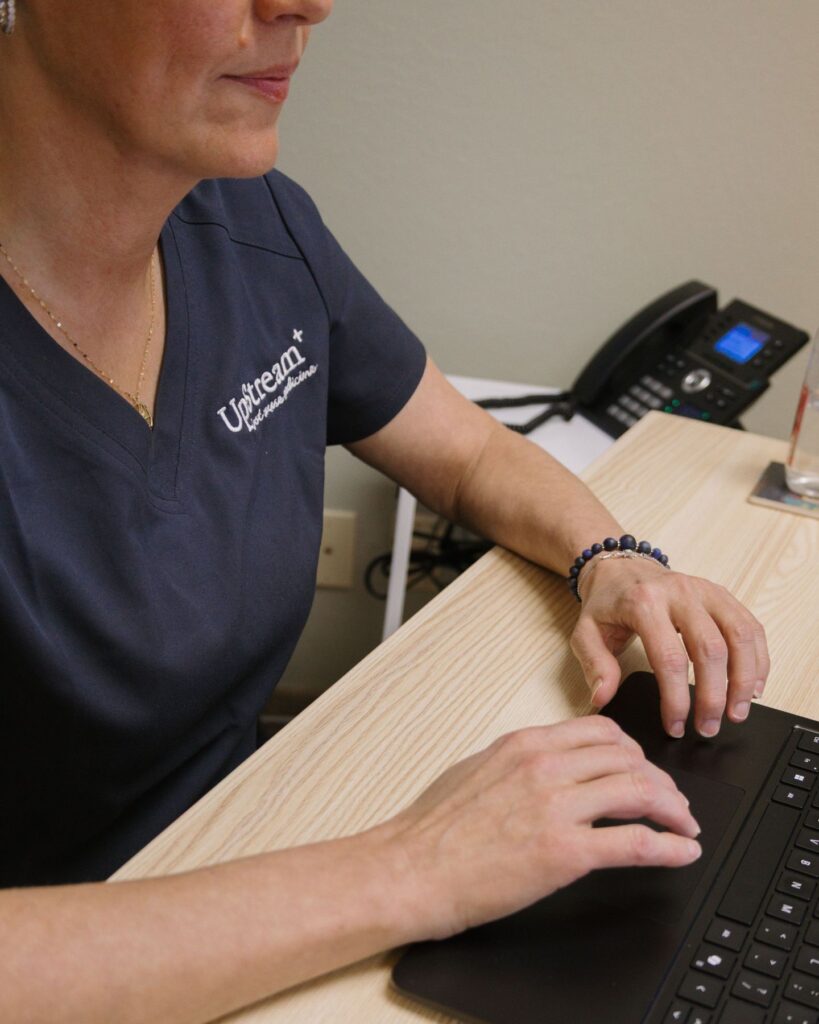 UpStream Root Cause Medicine clinician working at desk, representing integrative medicine Omaha focused on personalized, coordinated care.