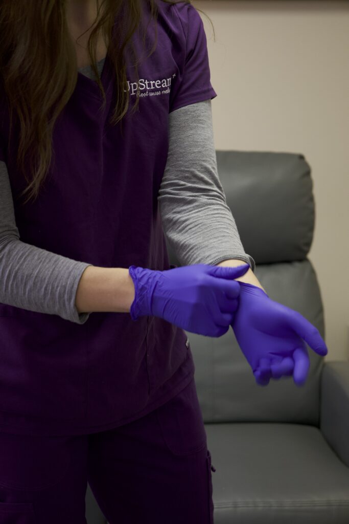 Clinician putting on gloves in a treatment room at an Omaha systems based functional medicine clinic.