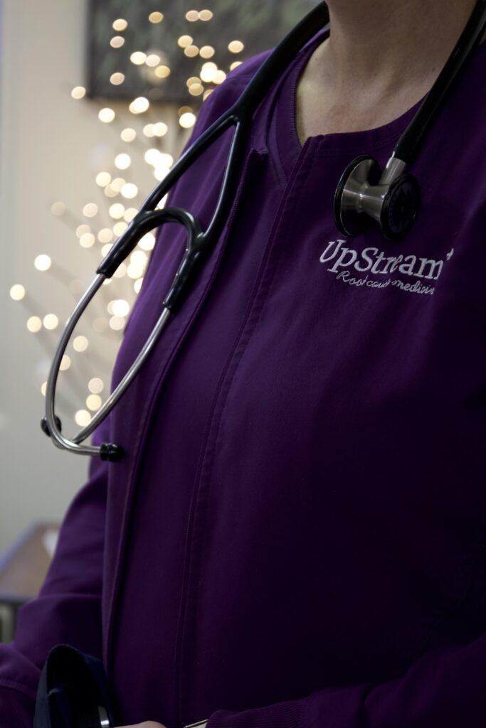 Clinician wearing an UpStream Root Cause Medicine jacket with stethoscope, representing care for stress hormone imbalance Omaha.