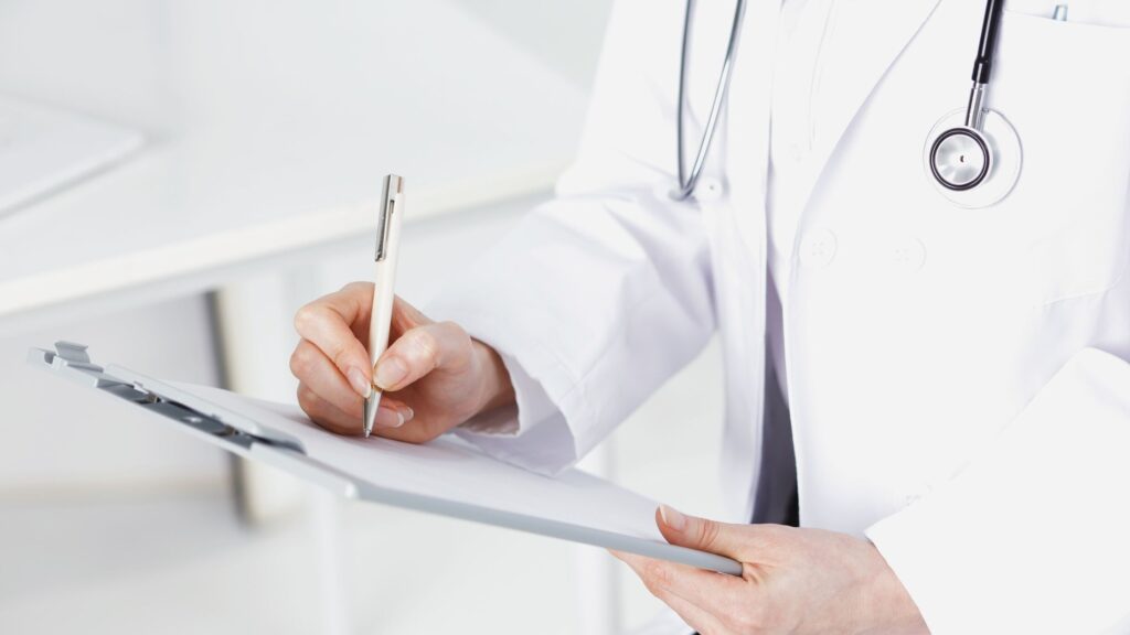 Clinician writing on a clipboard during a patient intake, representing the dashboard functional medicine Omaha approach.
